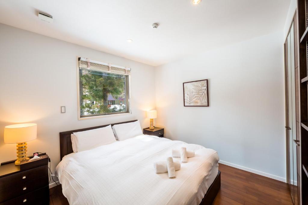 a bedroom with a white bed and a window at Phoenix Chalets by HHG in Hakuba
