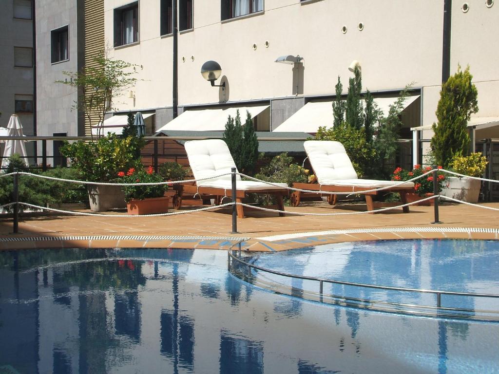 una piscina con 2 tumbonas junto a un edificio en Hotel & Spa Real Jaca, en Jaca