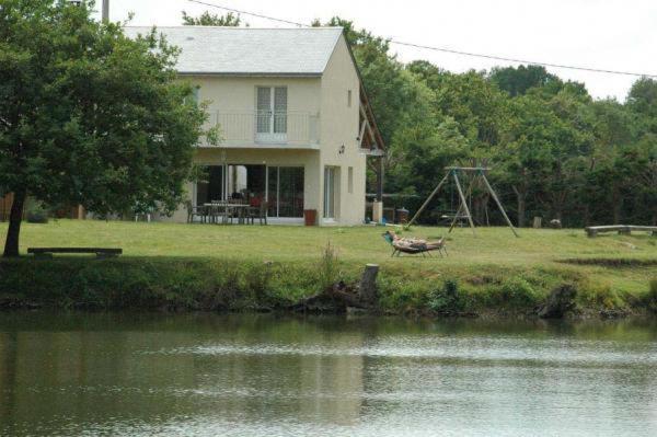 una casa con un'altalena accanto a un corpo d'acqua di L'Autourserie a Chahaignes