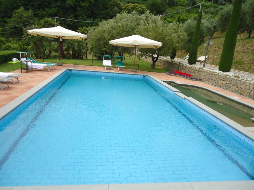 a large blue swimming pool with chairs and umbrellas at Monte A Pescia in Pescia