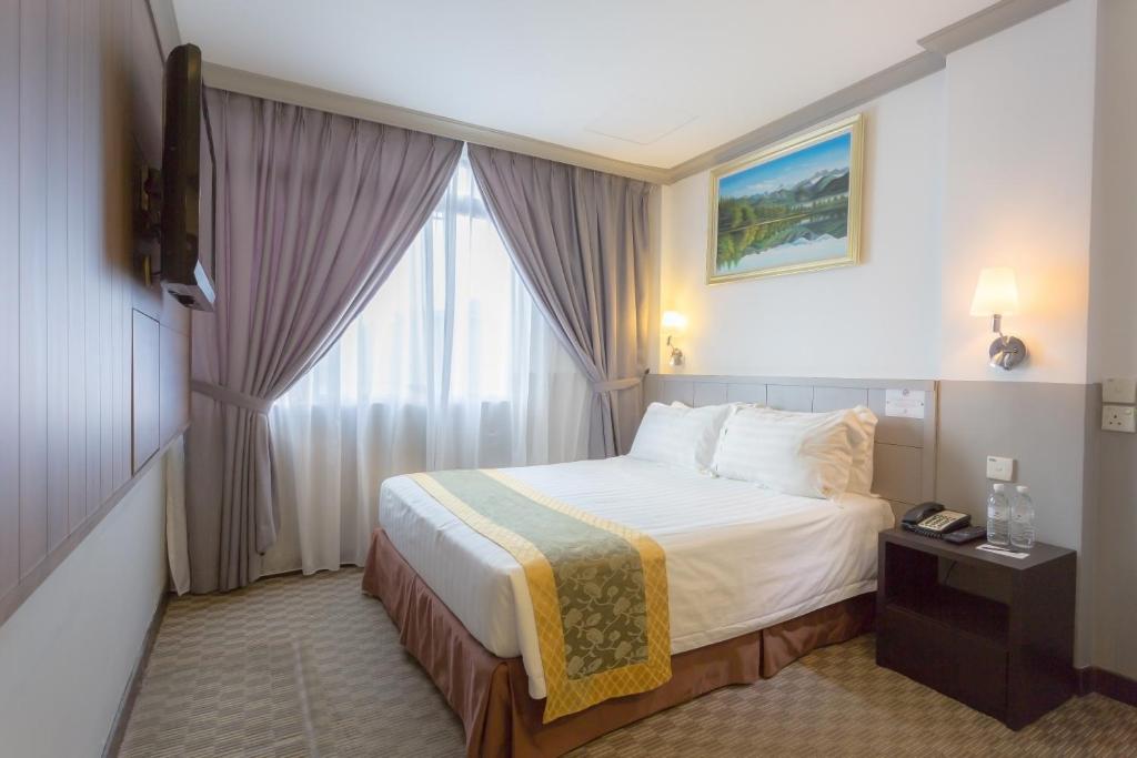 a hotel room with a bed and a window at Hallmark Leisure Hotel in Melaka