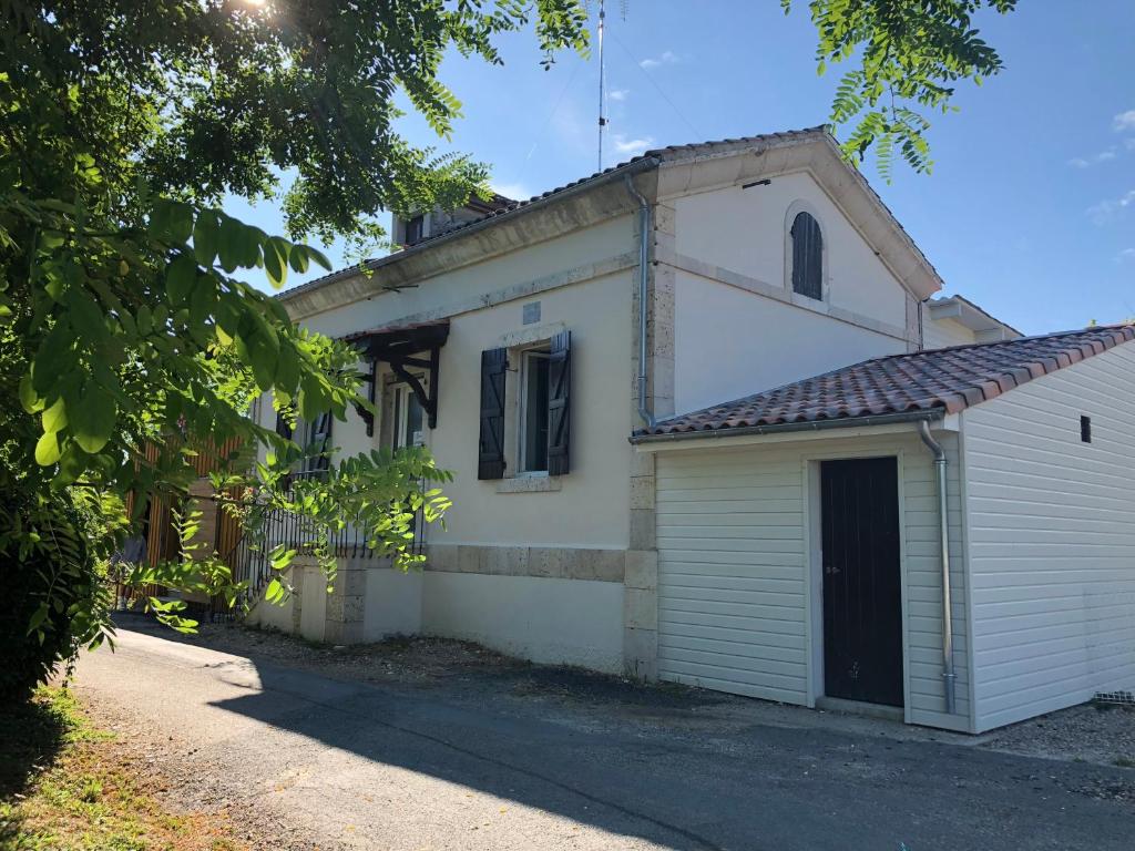 a small white building with a black door at L’île aux Bateaux in Buzet-sur-Baïse