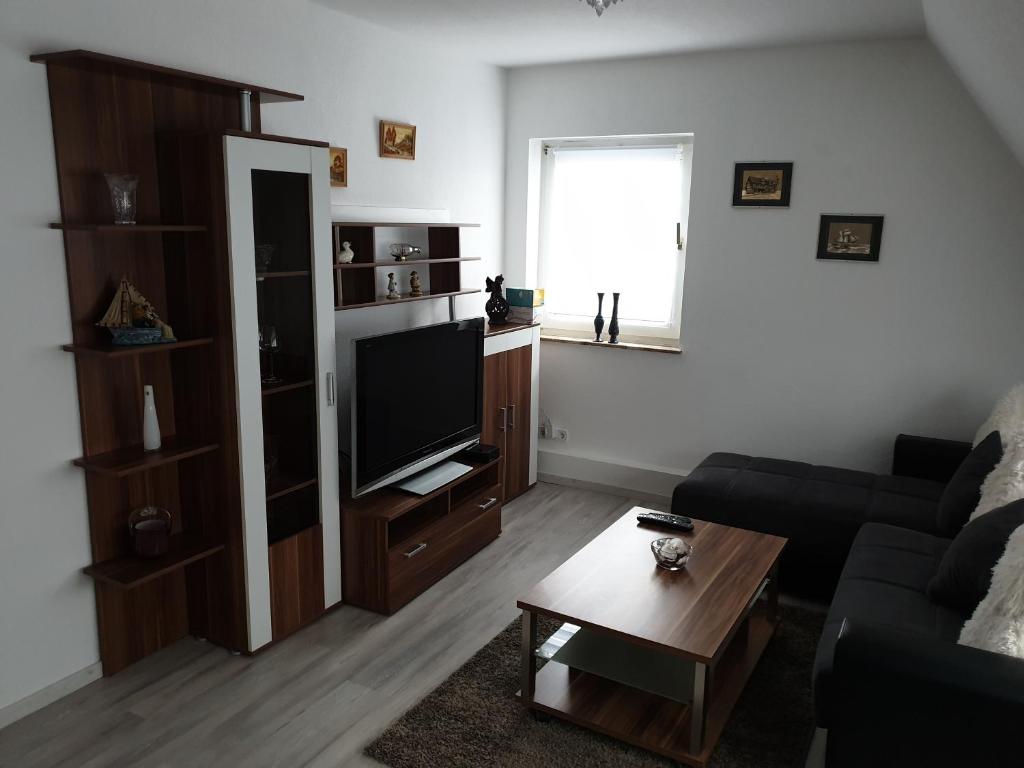 sala de estar con sofá y TV de pantalla plana en Ferienwohnung Helena en Emden