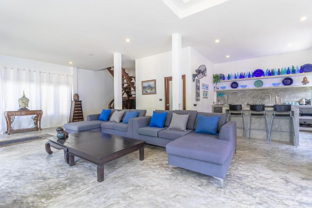 a living room with couches and a table and a kitchen at Aloe Villa in Koh Tao