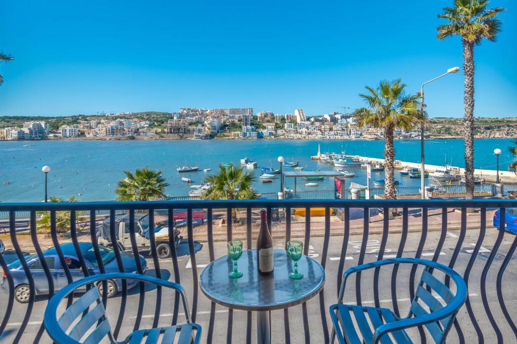 una mesa y sillas en un balcón con vistas al agua en Harbour Lights seafront 2 bedroom apartments with panoramic sea views - by Getawaysmalta en St Paul's Bay