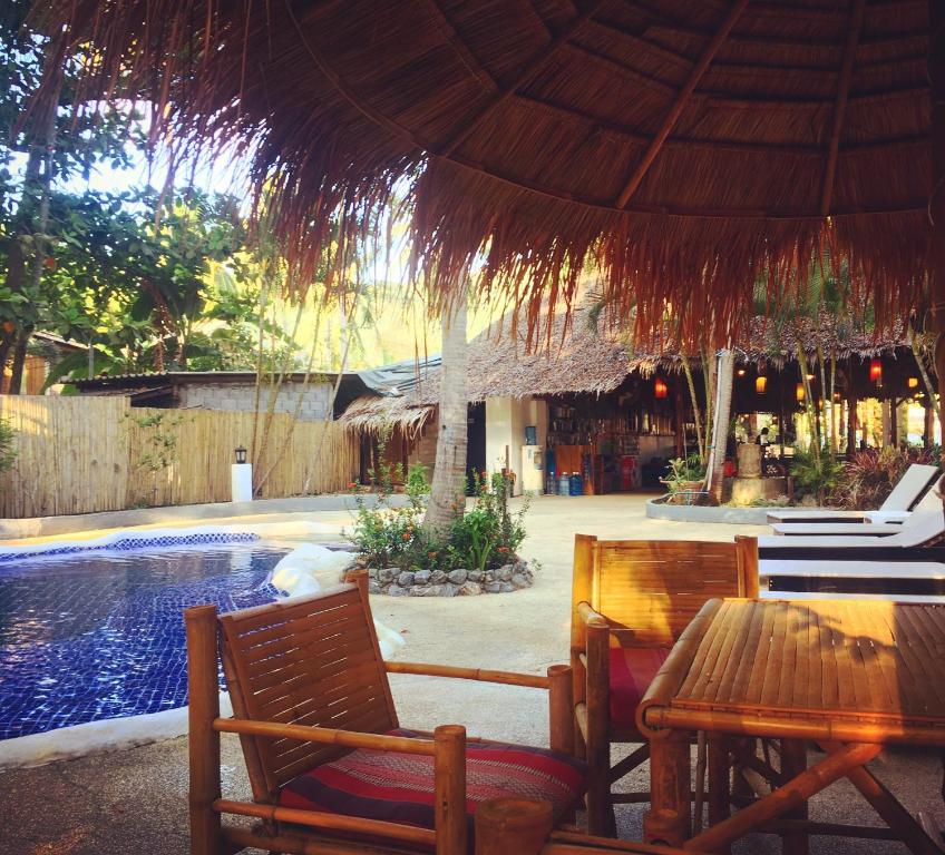 a patio with a table and chairs and a swimming pool at Papillon Bungalows in Ko Lanta