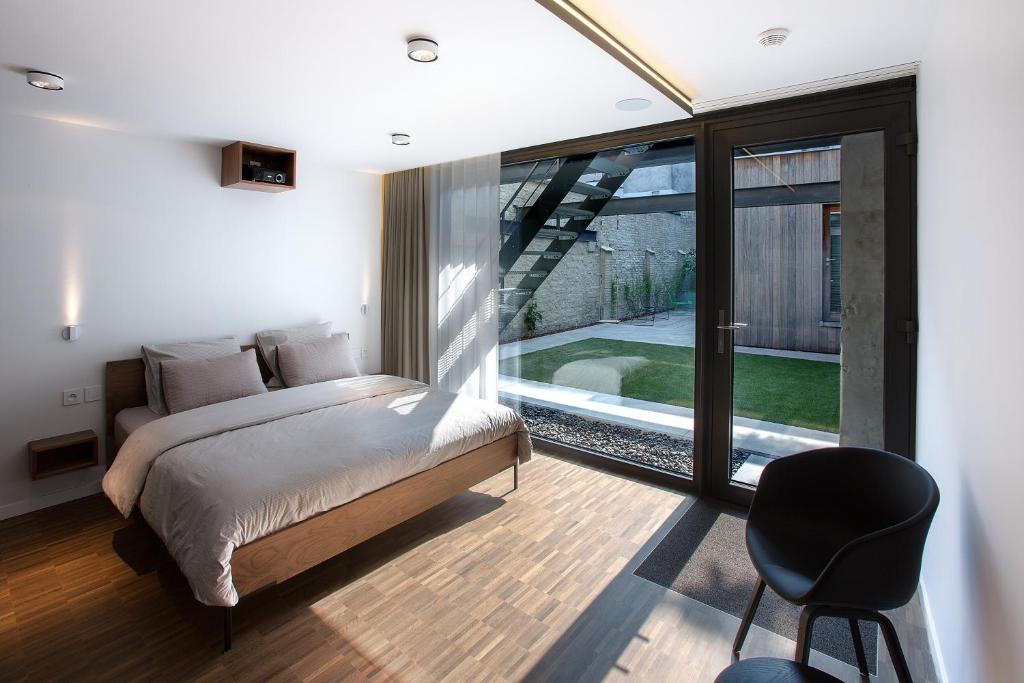 een slaapkamer met een bed, een stoel en een raam bij B&B Snooz Inn in Gent