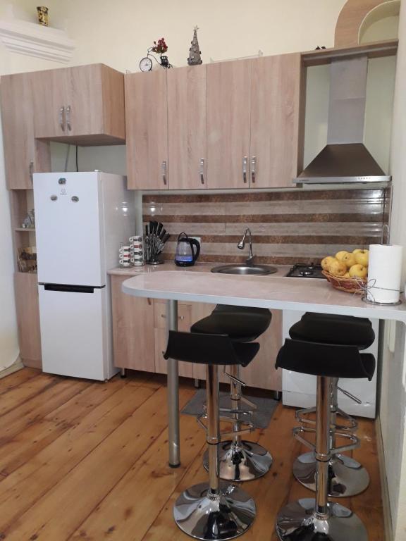a kitchen with a white refrigerator and a counter with stools at Sololaki Dadiani in Tbilisi City