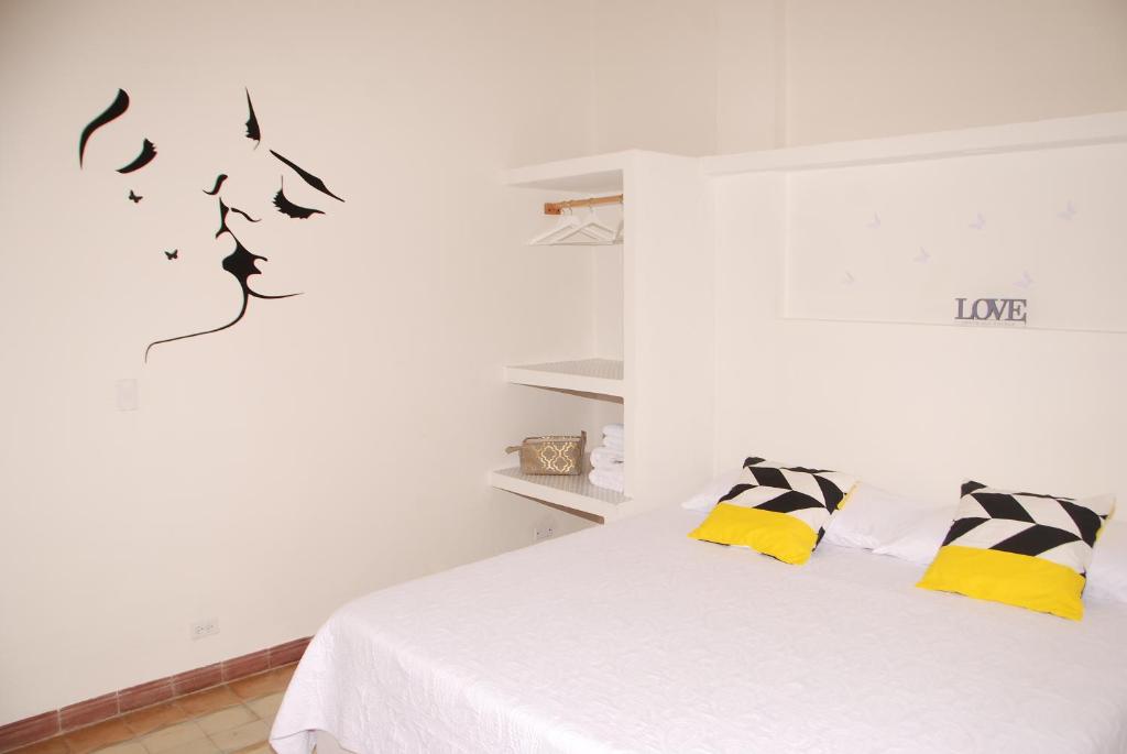 Dormitorio blanco con cama con almohadas amarillas y negras en Casa Violeta, en La Habana