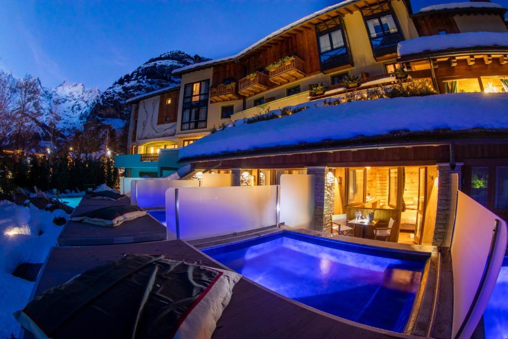 a house with a swimming pool in the snow at Gran Baita Hotel & Wellness in Courmayeur