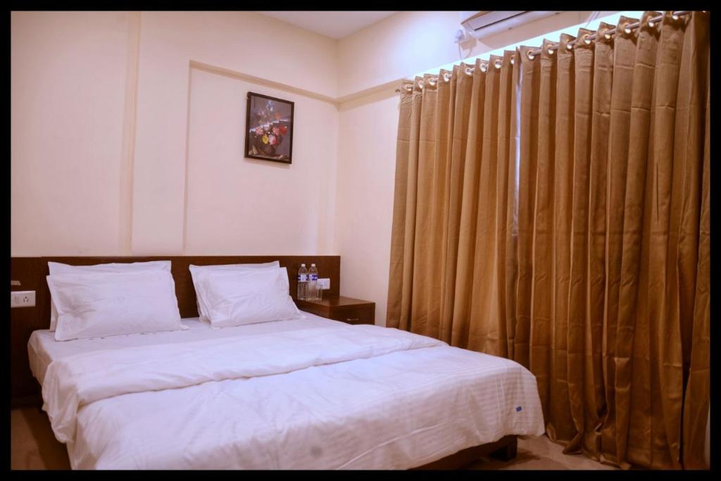 a bedroom with a bed and curtains in it at Malhar Grand in Jejūri
