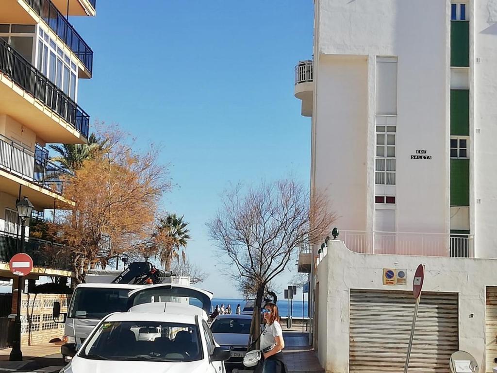 Eine Frau steht neben Autos, die neben einem Gebäude geparkt sind. in der Unterkunft Apartamento Decada Reyes Catolicos in Fuengirola