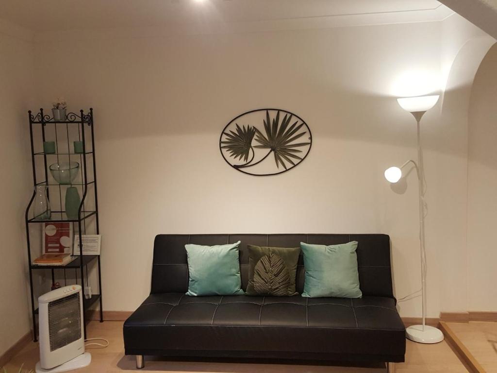 um sofá preto numa sala de estar com um relógio na parede em Casa S. Tiago em Setúbal