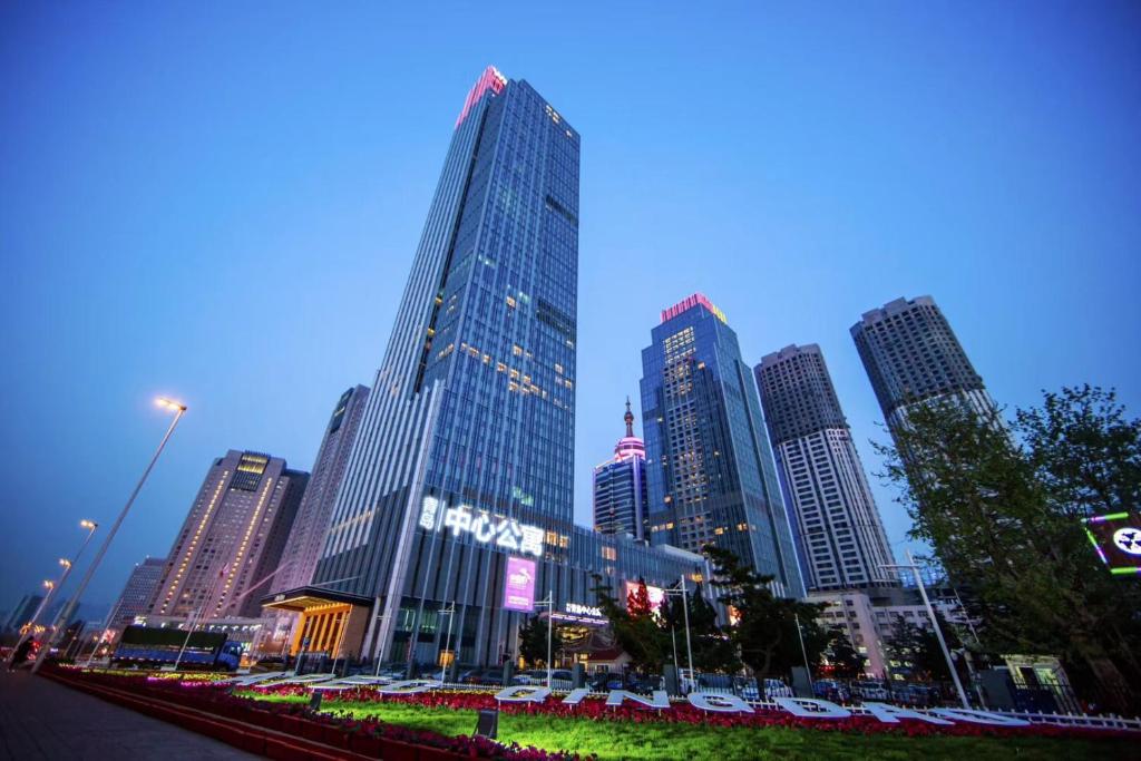 a city skyline with tall skyscrapers at night at Qingdao Elegant Central Apartment in Qingdao