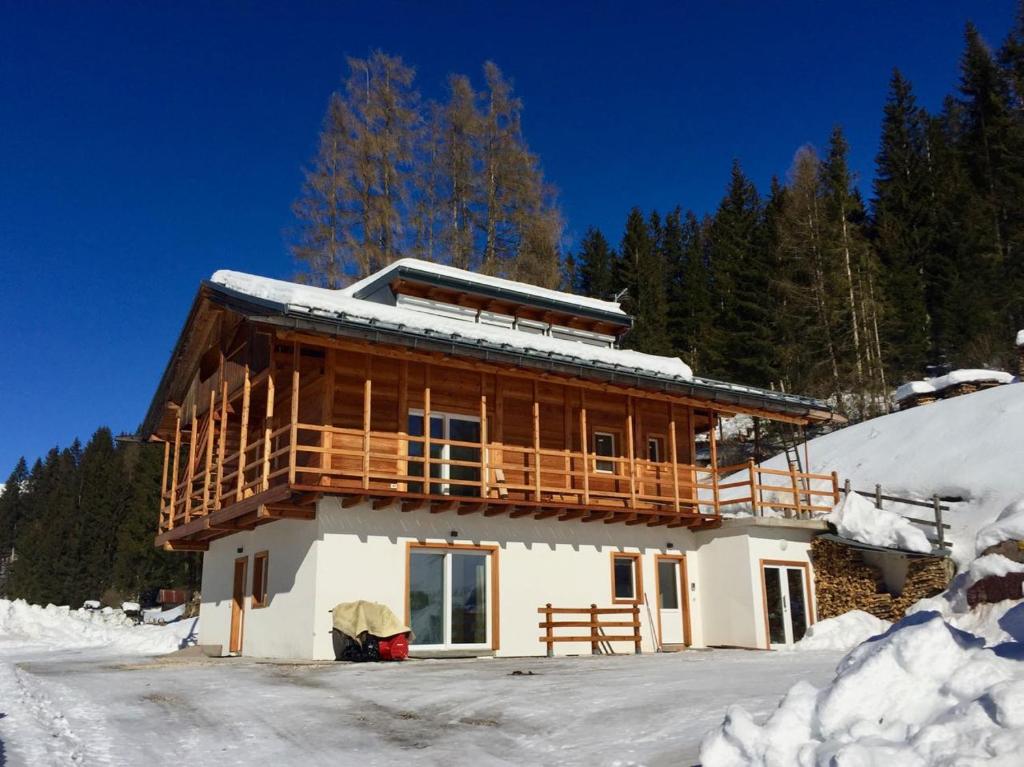 a large wooden house with a balcony in the snow at Agriturismo Moiè in Comèlico Superiore