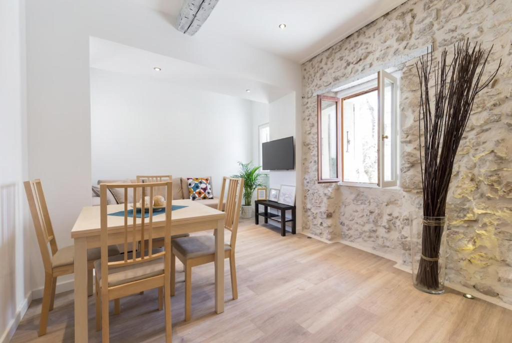 une salle à manger avec une table et des chaises et un mur en pierre dans l'établissement VUE PICASSO - Agréable 2P vue musée Picasso et Mer, à Antibes