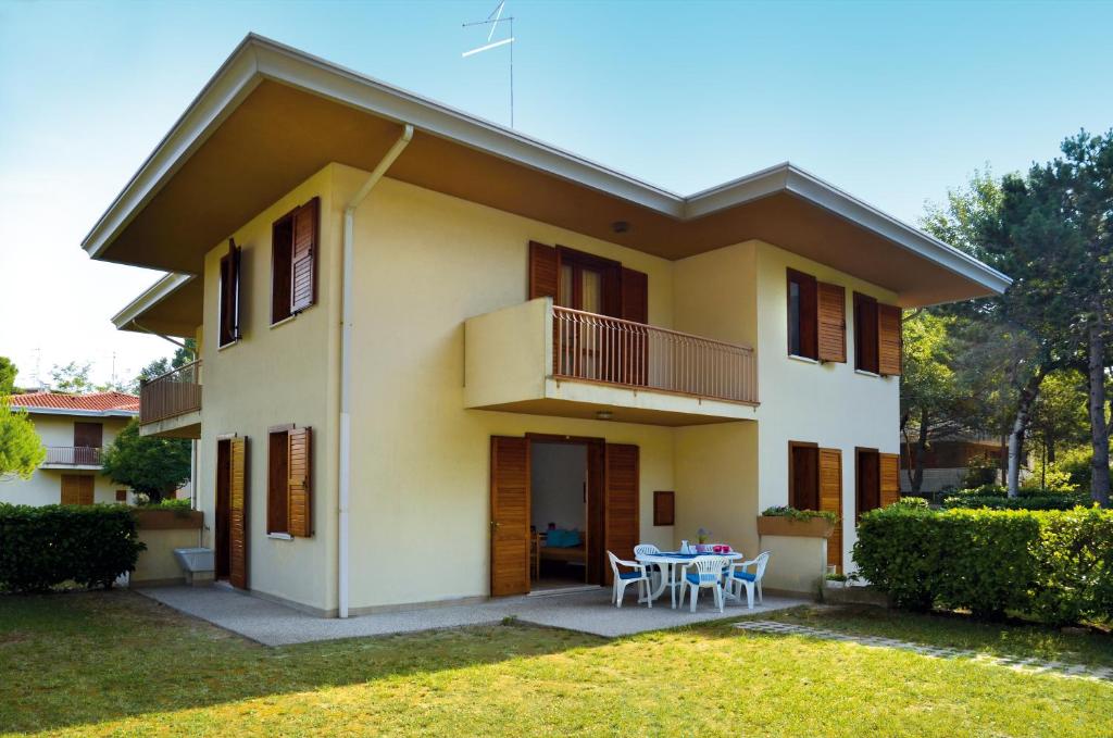 een huis met een tafel en stoelen in de tuin bij Ville Carla e Caterina in Bibione