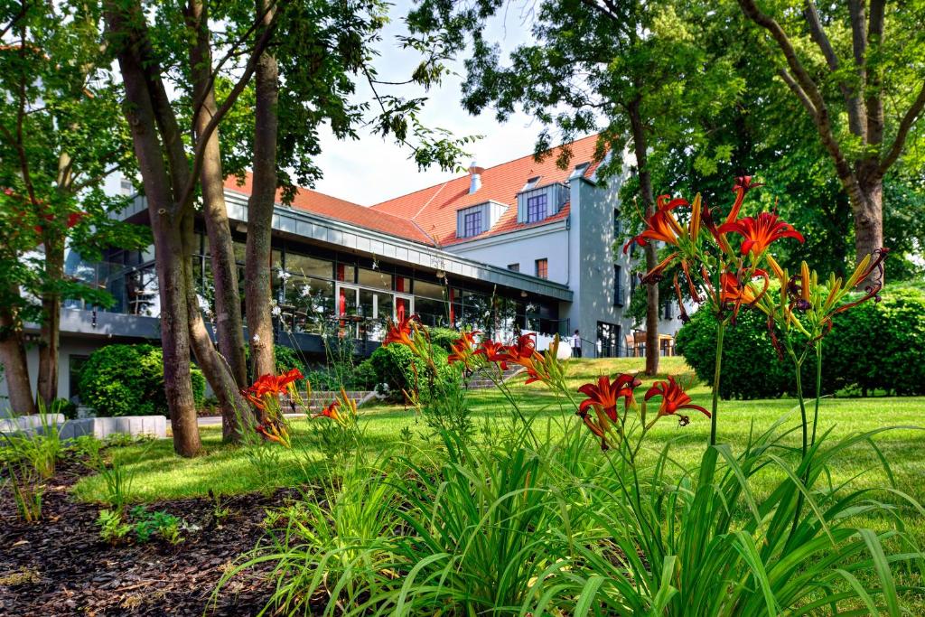 a garden with red flowers in front of a building at ARTHOTEL Kiebitzberg in Havelberg