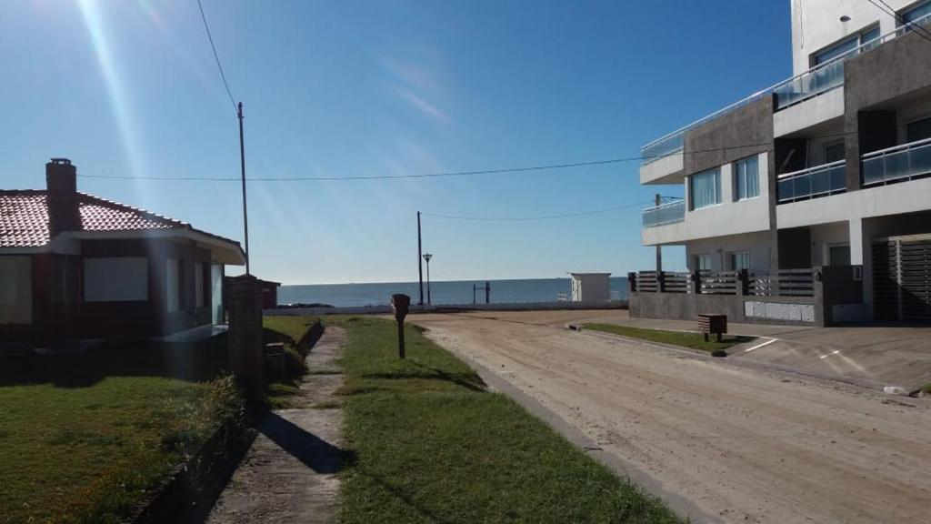 un chemin de terre à côté d'un bâtiment avec l'océan dans l'établissement Villa Bono, à Santa Clara del Mar