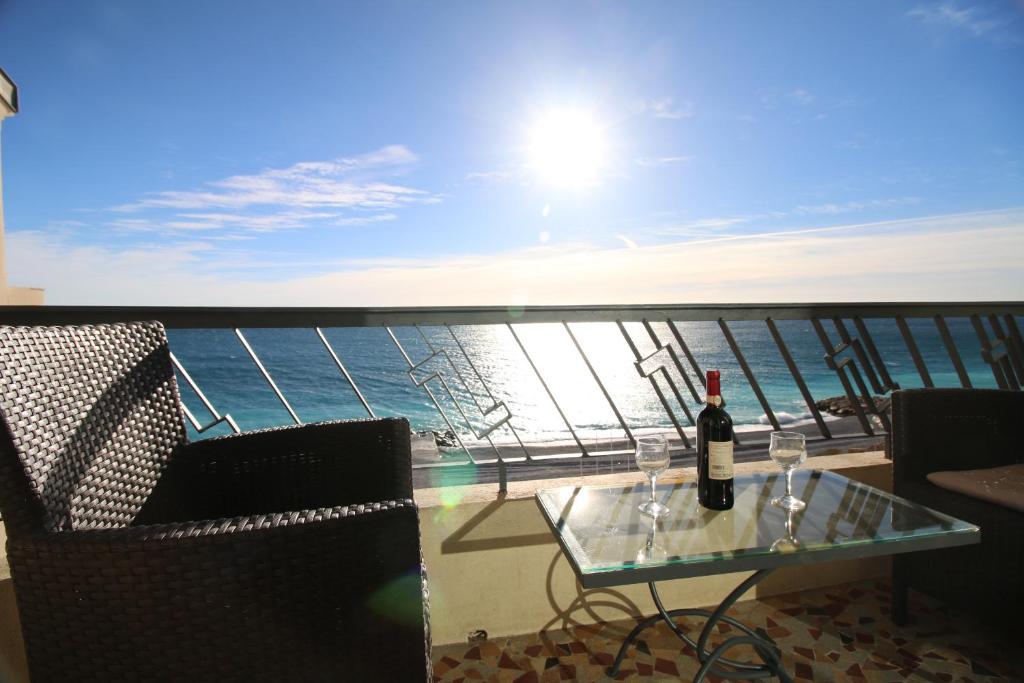 - une table en verre avec une bouteille de vin sur le balcon dans l'établissement Promenade des anglais Vue mer, à Nice