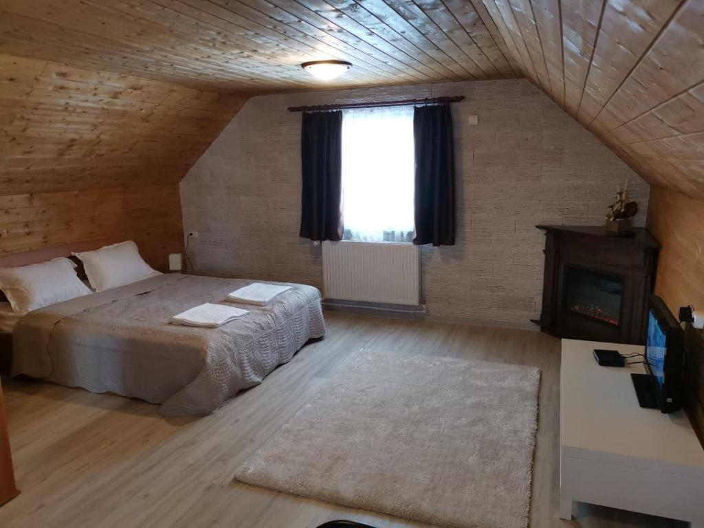 a bedroom with a bed and a window and a fireplace at Somogyi Vendégház in Bancu