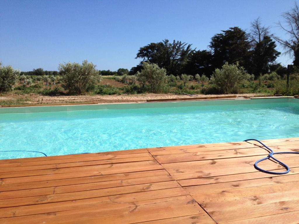 een zwembad met blauw water op een houten terras bij Domaine de l'Aumone in Agde
