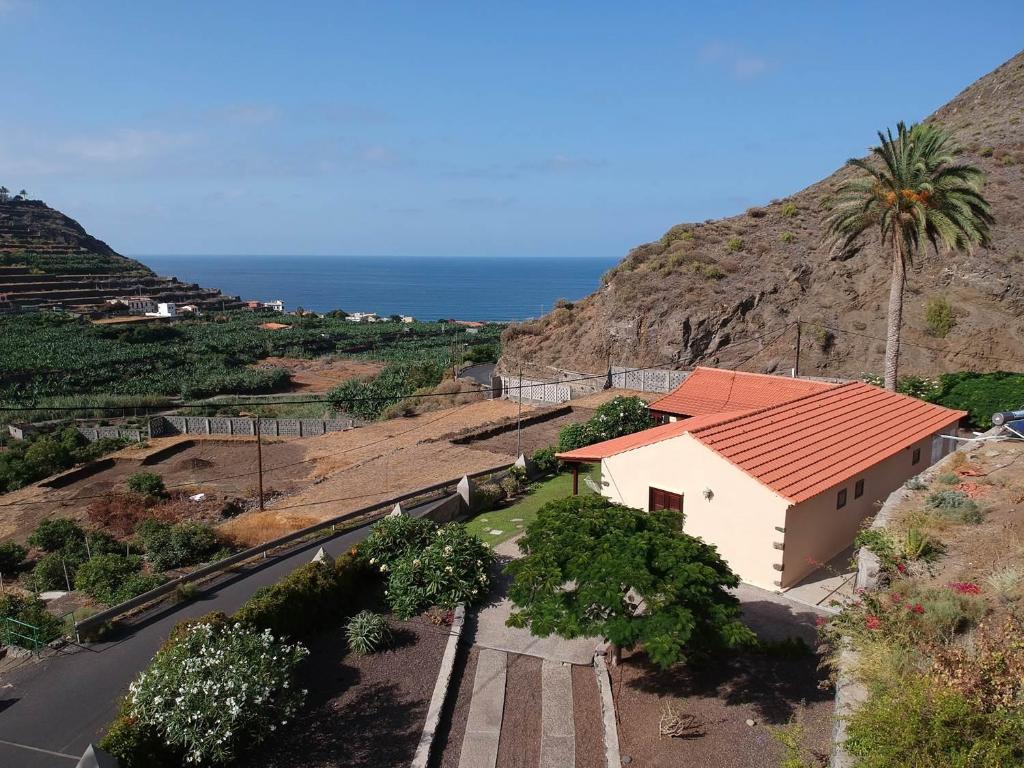 a house on a hill with a palm tree and a road at Gomera Garden. Vista Mar Altozano in Hermigua