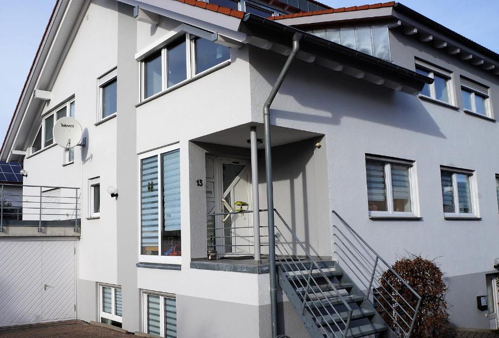 una casa bianca con una scala che porta alla porta d'ingresso di BodenSEE Apartment "La Musica" a Meckenbeuren