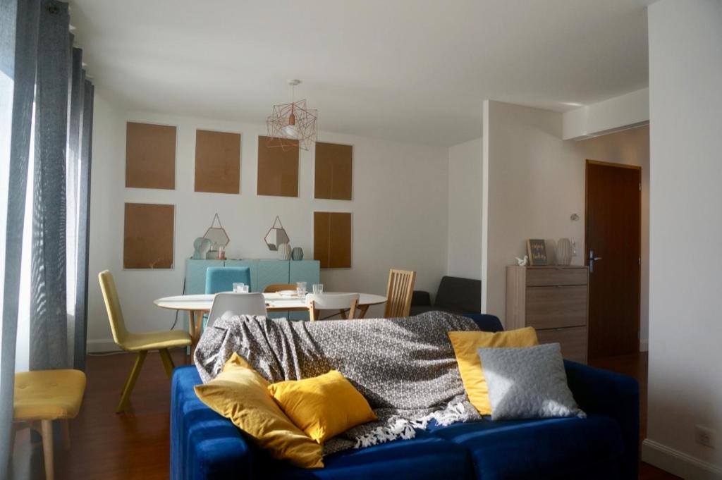 a living room with a blue couch with yellow pillows at Le 27 - Cosy appartement centre-ville - WIFI in Royan