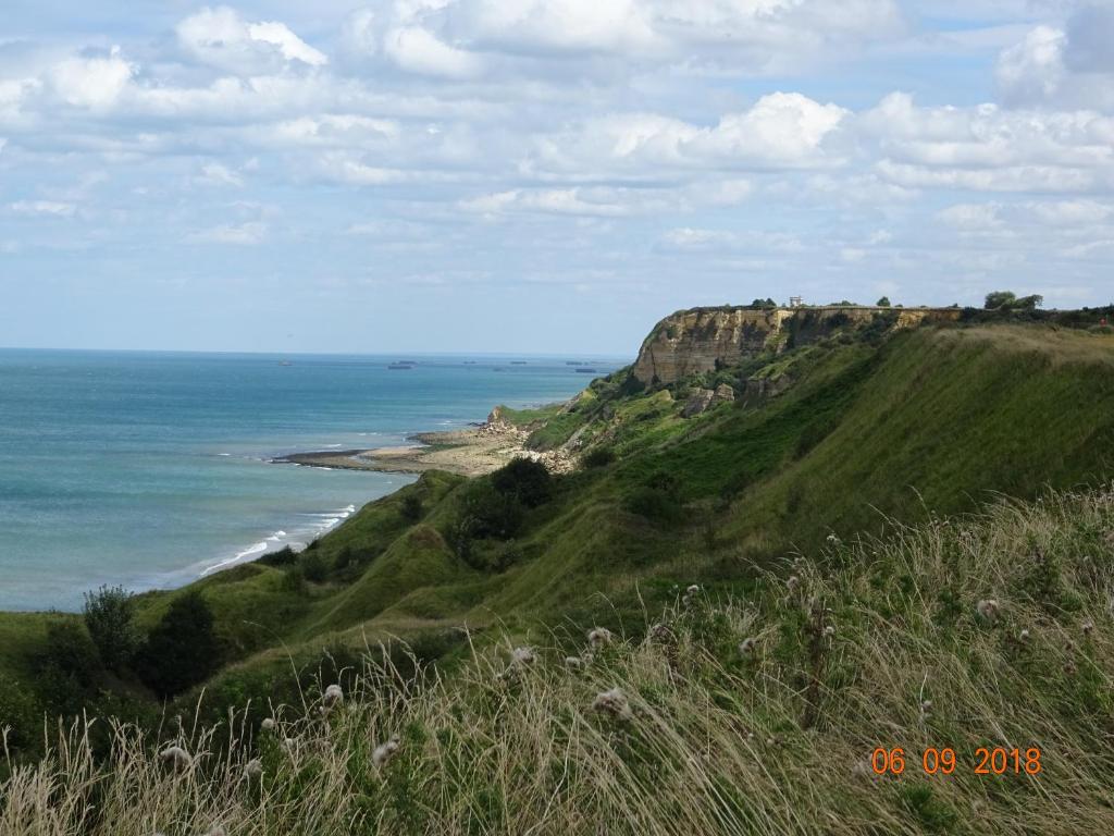 a view of the ocean from a hill with a beach at La ferme aux chats in Formigny