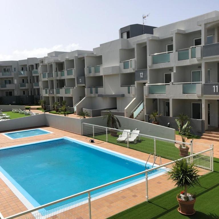 an apartment with a swimming pool in front of a building at Luxury Apartment in Corralejo