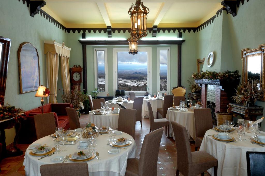 a restaurant with white tables and chairs and a chandelier at Hotel Villa Dorata in Nicolosi