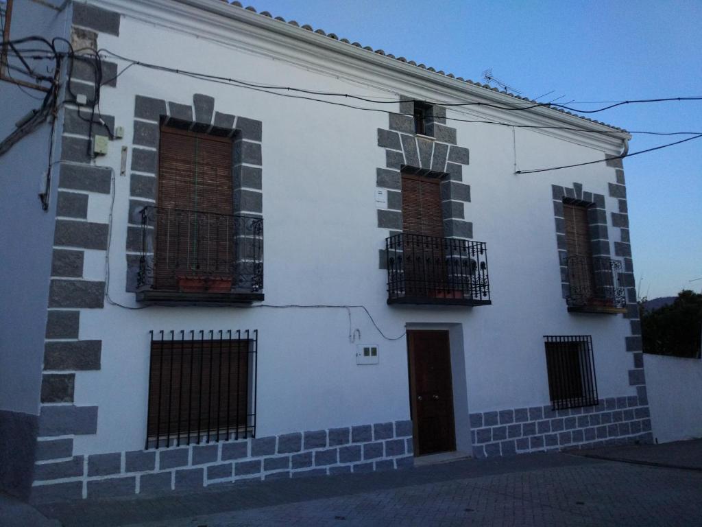 ein weißes Gebäude mit drei Fenstern und einer Tür in der Unterkunft Casa Rural Vega del Tajuña in Armuña de Tajuña