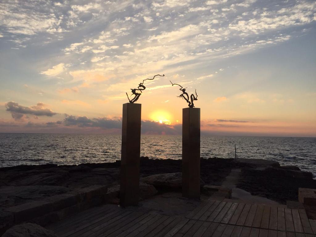 two sculptures on a pier with the sunset in the background at Holiday beach homes Romaní II in Colònia de Sant Jordi