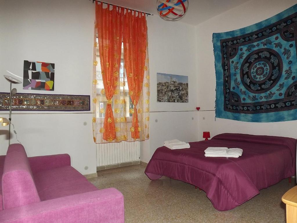 a bedroom with a purple bed and a couch at Casa Vacanze La Terra dei Briganti in Matera