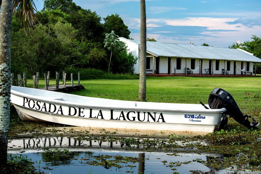 un barco sentado en el agua frente a un edificio en Posada de la Laguna en Colonia Carlos Pellegrini