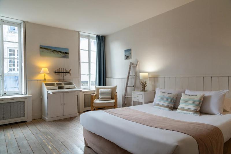 a hotel room with a large bed and a desk at Hôtel Saint-Laurent, The Originals Relais in Montfort-lʼAmaury