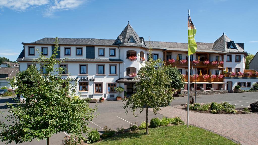 ein großes Gebäude mit einer Flagge davor in der Unterkunft MICHELS Wellness- & Wohlfühlhotel in Schalkenmehren