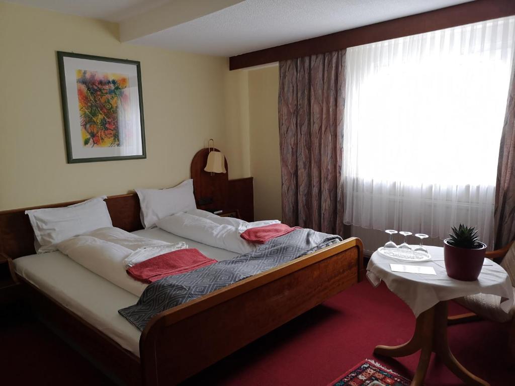 Schlafzimmer mit einem Bett, einem Fenster und einem Tisch in der Unterkunft Zum Erbacher Hof in Gadernheim