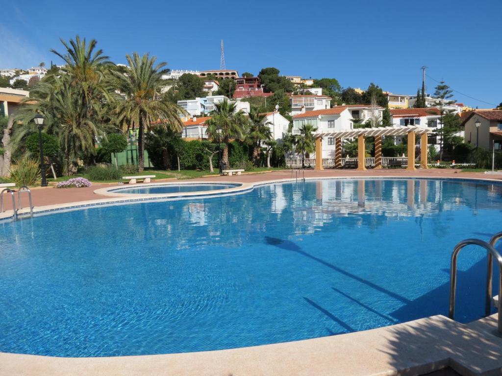 a large swimming pool with palm trees and houses at VILLA VICKY PEÑISCOLA, chalet pareado in Peñíscola