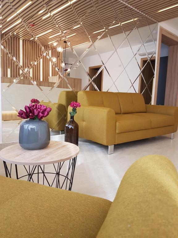 a living room with a couch and a table with flowers at YMY Boutique Residence in Bucharest