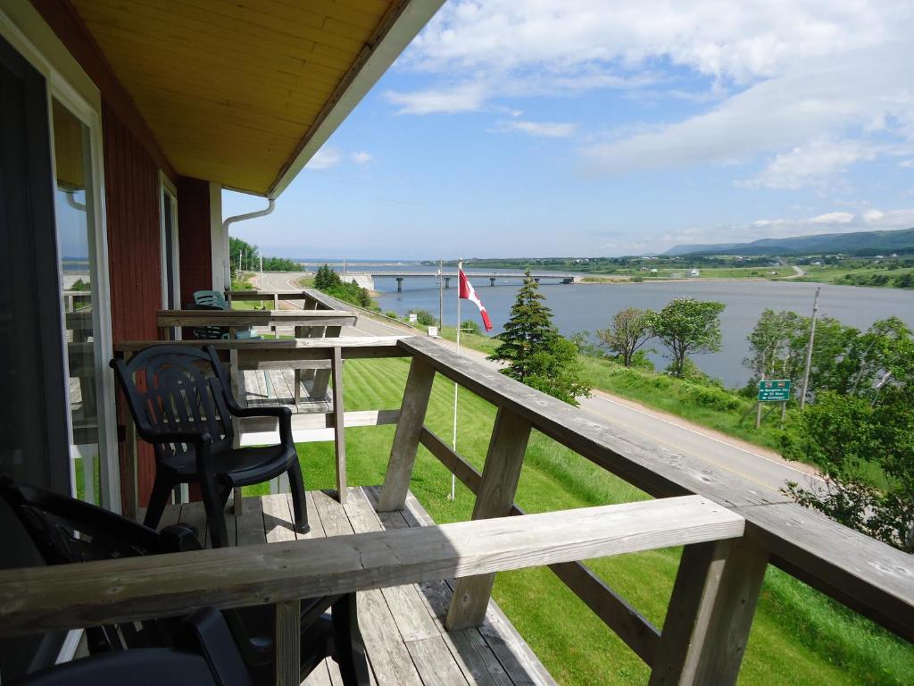 a porch with a table and chairs and a view of a river at Duck Cove Inn in Margaree Harbour
