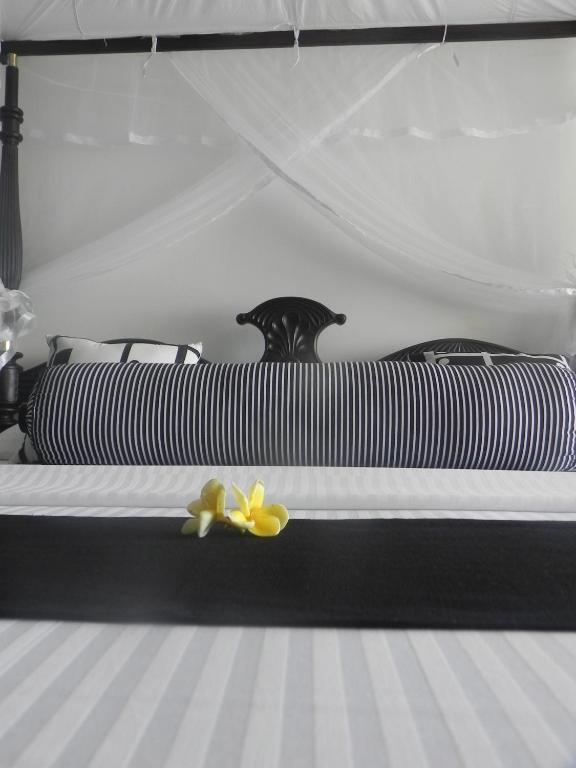a black and white bed with a yellow flower on it at Amanda Beach Villas in Unawatuna