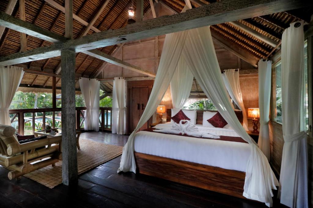 a bedroom with a bed and a desk in a room at Keramas Sacred River Retreat Resort and Villa in Keramas