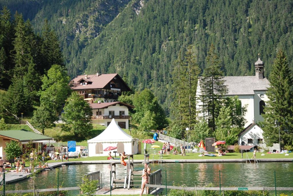 um grupo de pessoas em pé em uma doca em um lago em Ferienwohnung Pension Tirol em Bichlbach