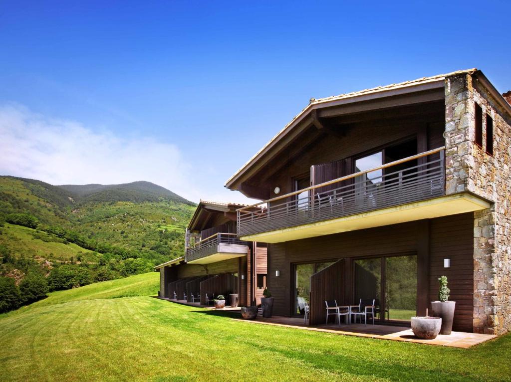 a house on a hill with mountains in the background at Hotel Rural-Spa Resguard Dels Vents in Ribes de Freser