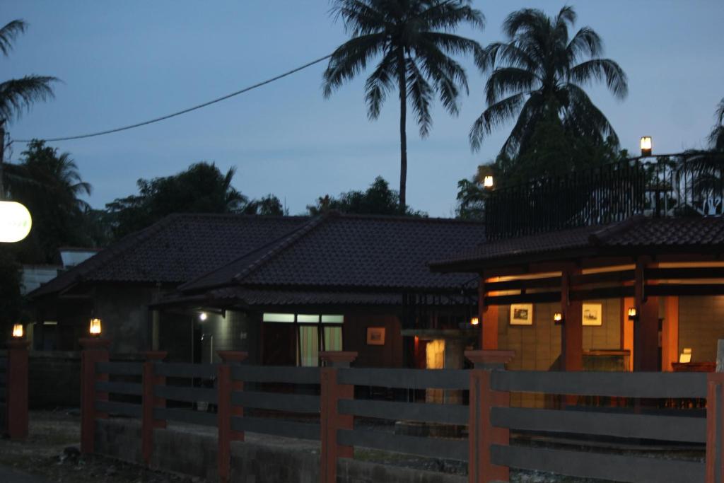 a house with a fence and palm trees at night at Amazon Bungalow & Cottages in Batukaras