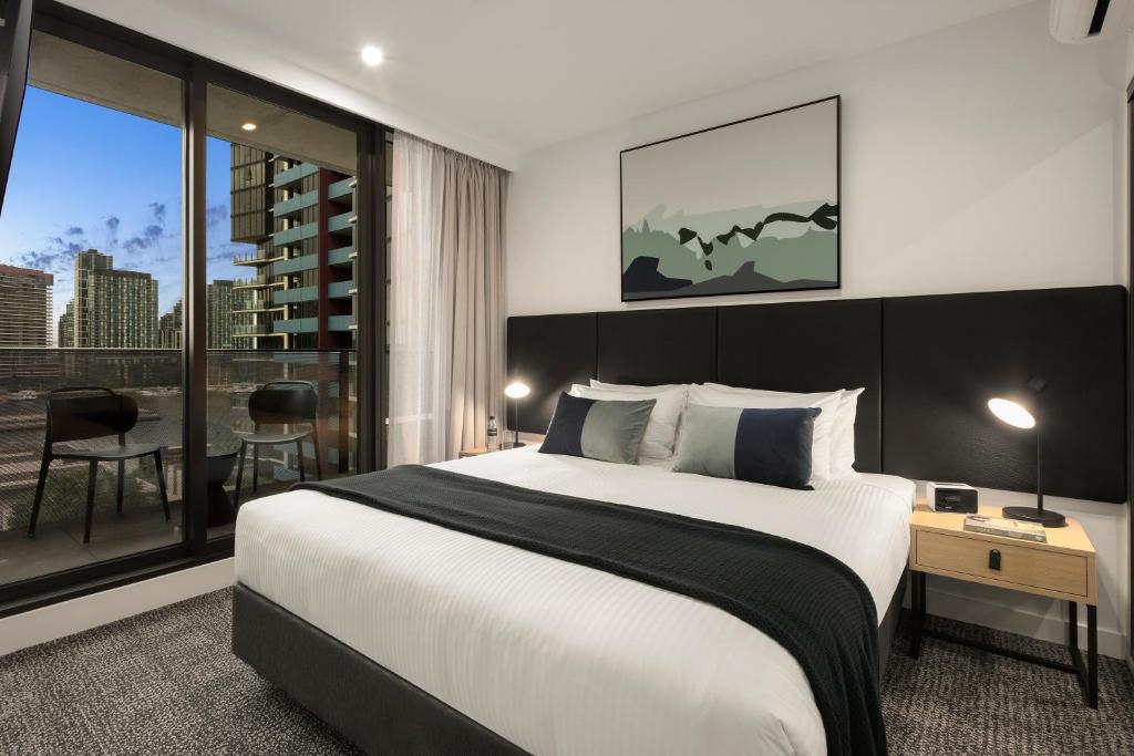a bedroom with a large bed and a large window at Quest NewQuay in Melbourne
