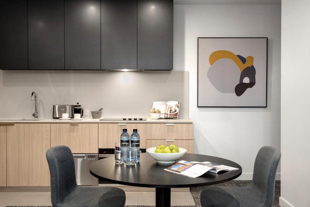 a kitchen with a black table and chairs and a counter at Quest NewQuay in Melbourne