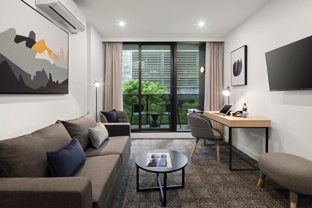 a living room with a couch and a desk at Quest NewQuay in Melbourne